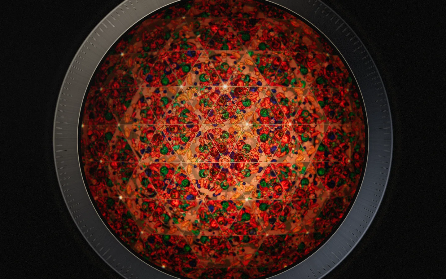 The view through the eyepiece: triangular reflections of red, green, blue and amber glass form a star-shaped pattern lit warm orange from behind, inside a brushed-metal rim with engraved ticks