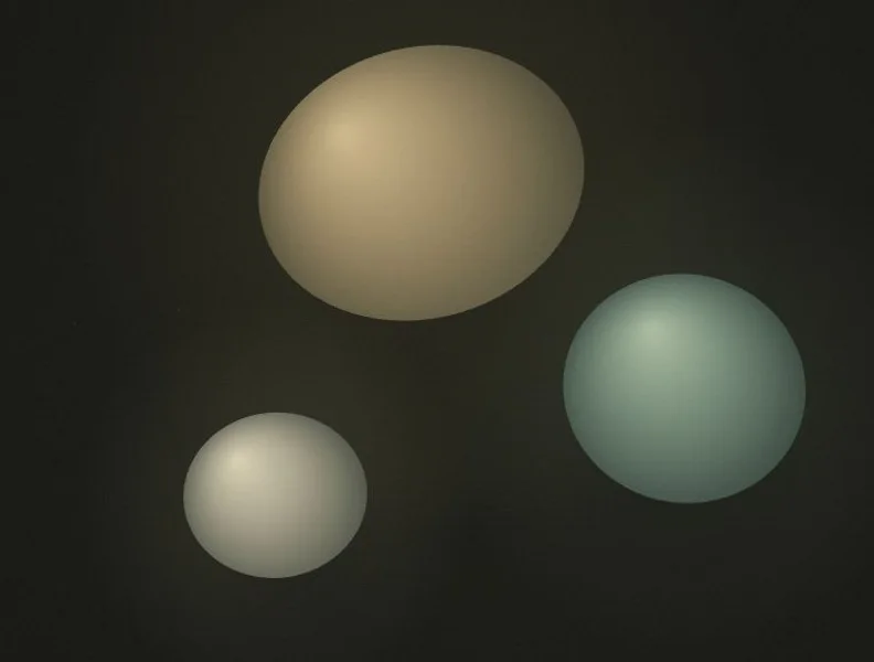 Three softly illuminated oval forms in a dark mineral field
